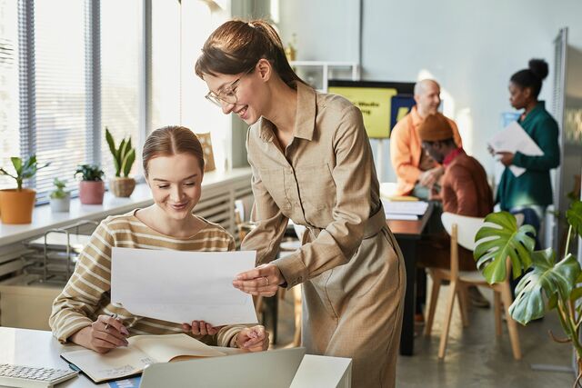Zwei Frauen schauen sich in einem Büro eine Unterlage an.