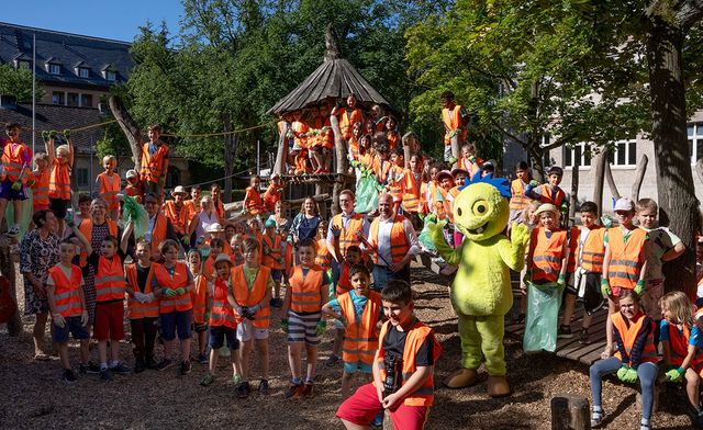Kinder in Warnwesten mit Maskottchen Müllmo